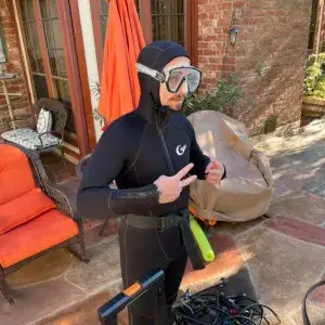 Pool leak detection technician geared up in a wetsuit and dive mask ready for underwater inspection