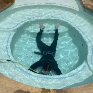 Underwater view of a scuba diver inspecting the pool main drain for leaks on the spa floor